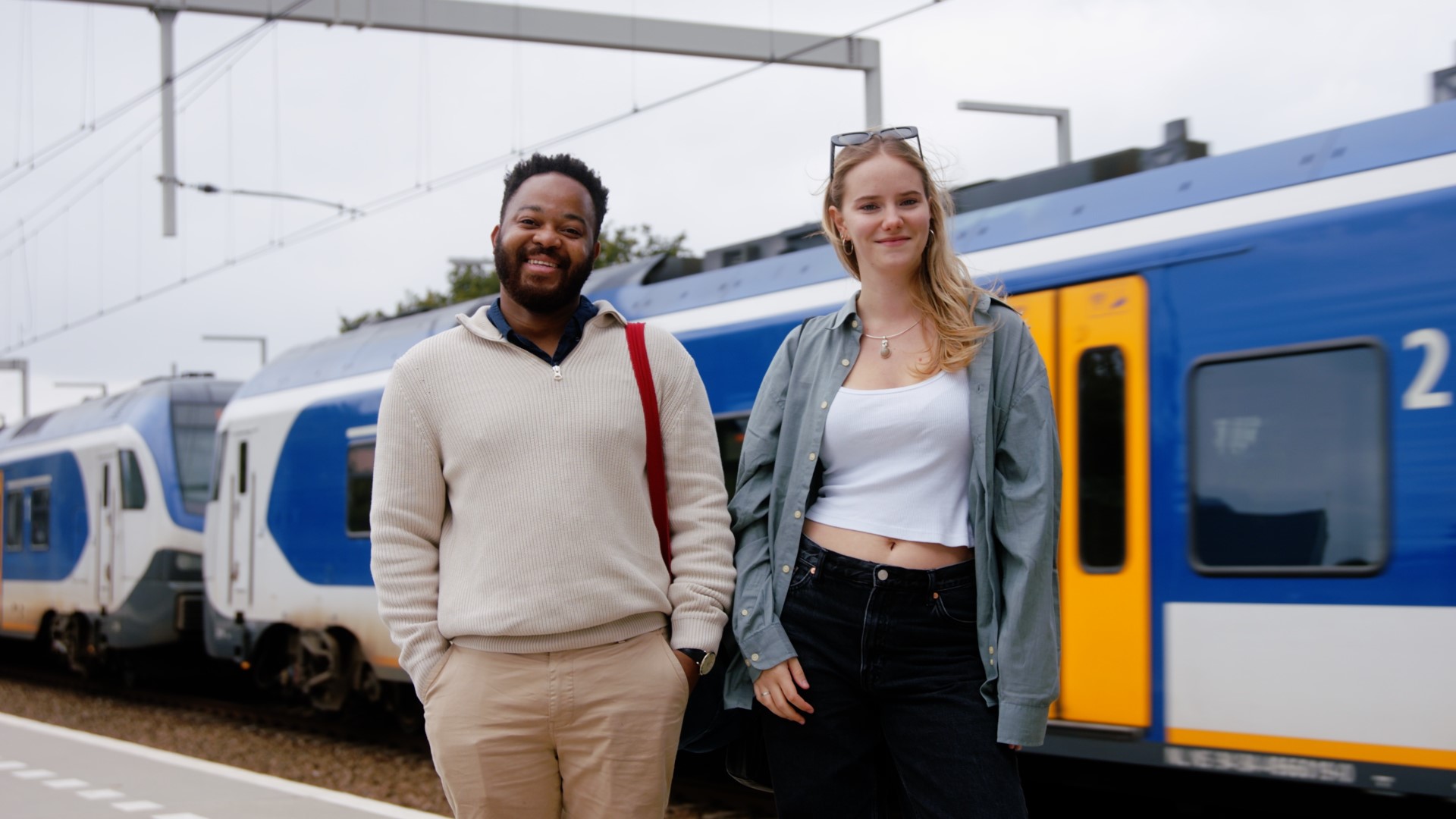 Twee jongeren die voor een trein staan.